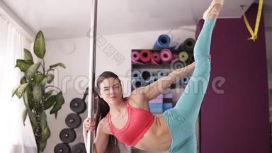 年轻美丽的女人正在伸展和热身，靠在健身房的一根柱子上，上面有各种颜色的<strong>垫子</strong>和<strong>垫子</strong>